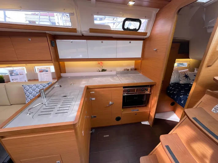  Yacht Photos Pics Modern kitchen interior of 2022 Dufour 390 Grand Prix sailboat, featuring sleek wood cabinetry.