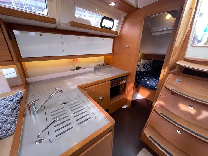  Yacht Photos Pics Modern kitchen interior of 2022 Dufour 390 Grand Prix sailboat, featuring sleek cabinetry and cozy sleeping area.