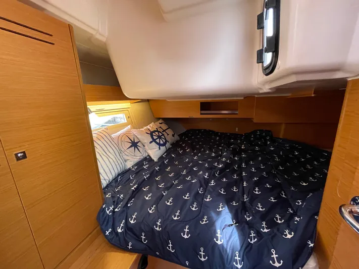  Yacht Photos Pics Cozy cabin interior of 2022 Dufour 390 Grand Prix sailboat with nautical-themed bedding.