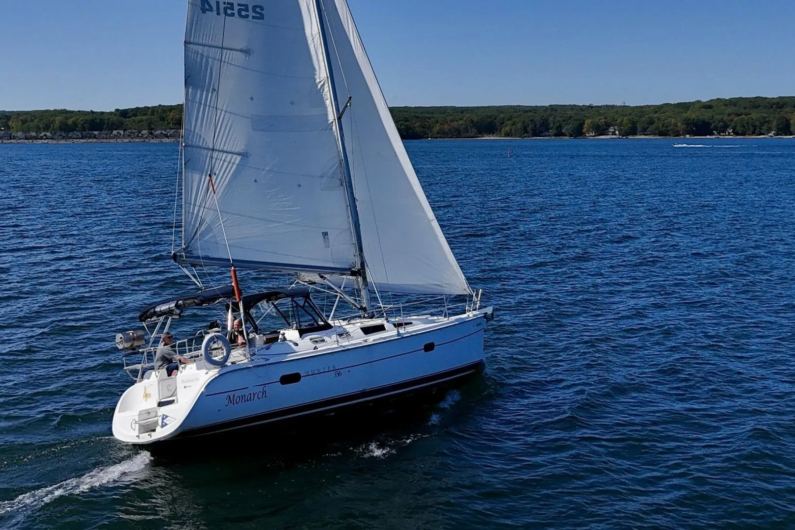 Sailing yacht Hunter 356, 2003 model, cruising on a serene blue lake.