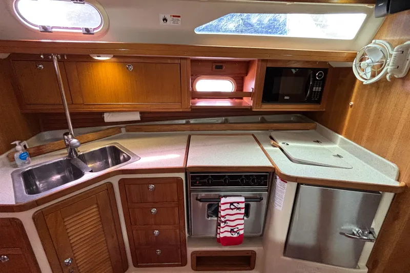  Yacht Photos Pics 2006 Catalina 42 MkII yacht kitchen with wooden cabinetry, sink, stove, and microwave.