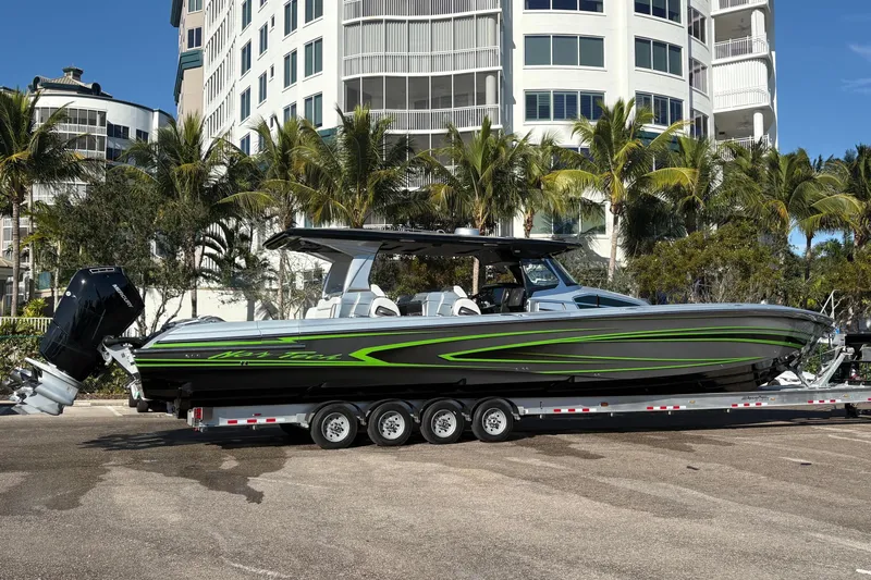  Yacht Photos Pics 2024 Nor-Tech boat with green accents on a trailer, parked near palm trees and buildings.