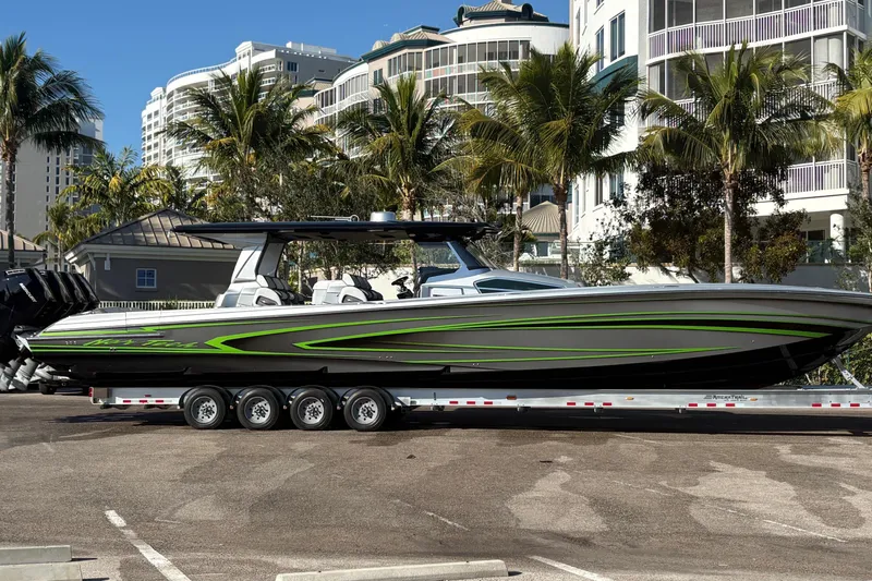  Yacht Photos Pics 2024 Nor-Tech boat with sleek design and green accents on a trailer, surrounded by palm trees.