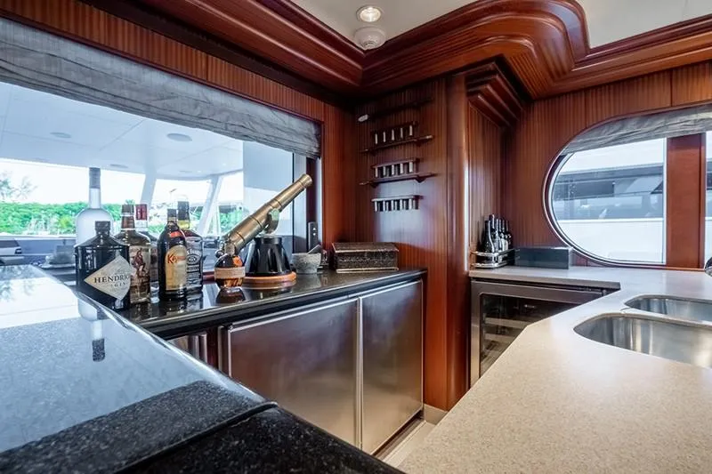 Never Enough Yacht Photos Pics Luxurious bar area on a 1992 Feadship 140 Tri-Deck yacht with wood accents and modern amenities.