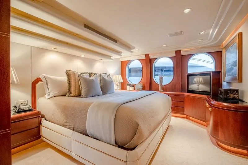 Never Enough Yacht Photos Pics Luxurious bedroom on a 1992 Feadship 140 Tri-Deck yacht with elegant wood finishes.