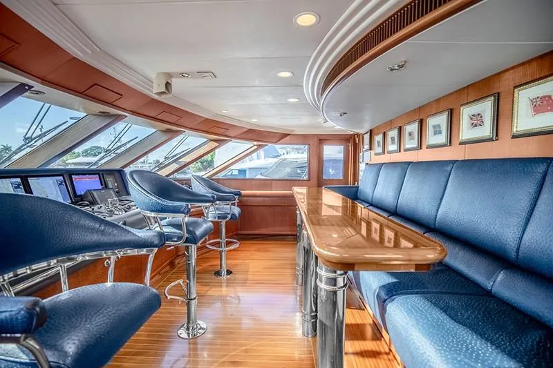 Never Enough Yacht Photos Pics Luxurious interior of 1992 Feadship 140 Tri-Deck yacht with blue seating and wooden accents.