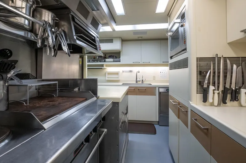 Never Enough Yacht Photos Pics Modern galley kitchen on 1992 Feadship 140 Tri-Deck yacht, featuring stainless steel appliances.