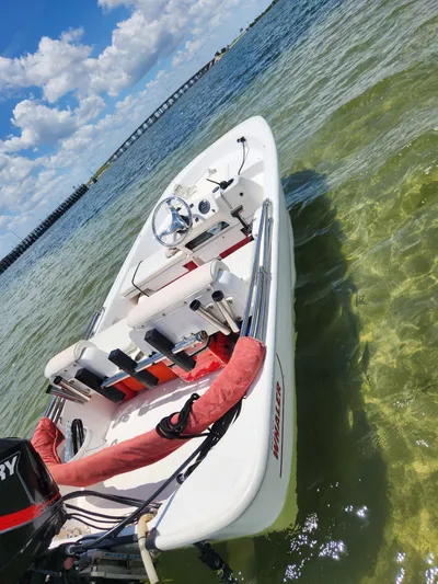 Wined Up Yacht Photos Pics A small white boat with a Mercury engine on clear water under a blue sky.