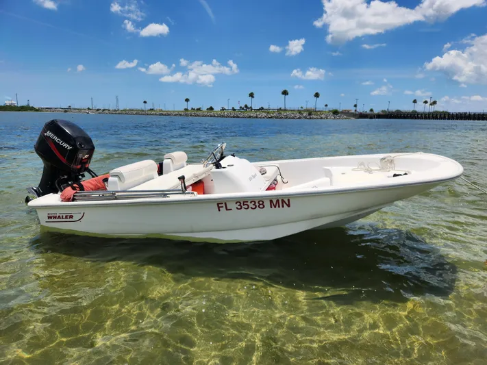 Wined Up Yacht Photos Pics A small Boston Whaler boat with Mercury engine on clear water under blue sky.
