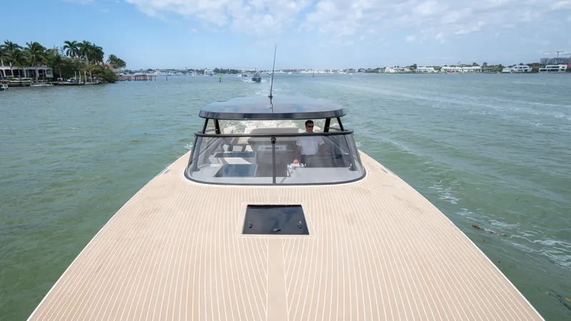  Yacht Photos Pics 2024 VanDutch 56 yacht cruising on a calm waterway under a partly cloudy sky.