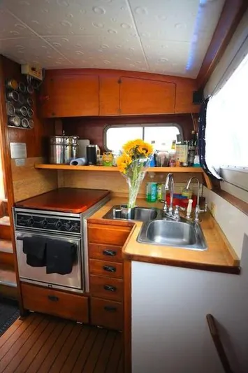 Hiolani II Yacht Photos Pics Cozy 1988 CSK Polycon boat kitchen with wood cabinets, stove, and sunflowers.