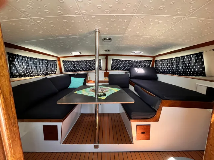 Hiolani II Yacht Photos Pics 1988 CSK Polycon boat interior with cozy seating and table, featuring nautical decor.