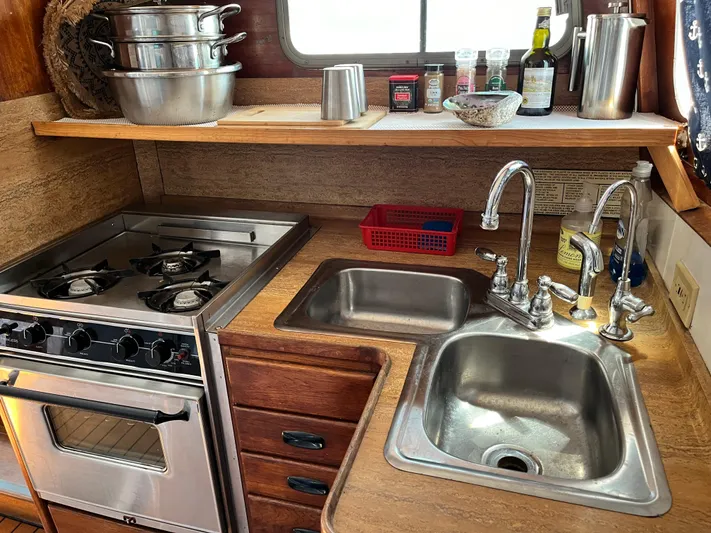 Hiolani II Yacht Photos Pics Compact 1988 CSK Polycon kitchen with stove, dual sinks, and wooden cabinetry.