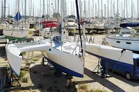 Custom TRIMARAN PULSAR 33 sailboat from 2002 in a boatyard, surrounded by other vessels.