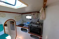 Interior of 2002 Custom TRIMARAN PULSAR 33, featuring compact kitchen with stove and storage.
