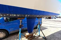 Bottom view of a 2002 Custom TRIMARAN PULSAR 33 on stands, with a blue van nearby.