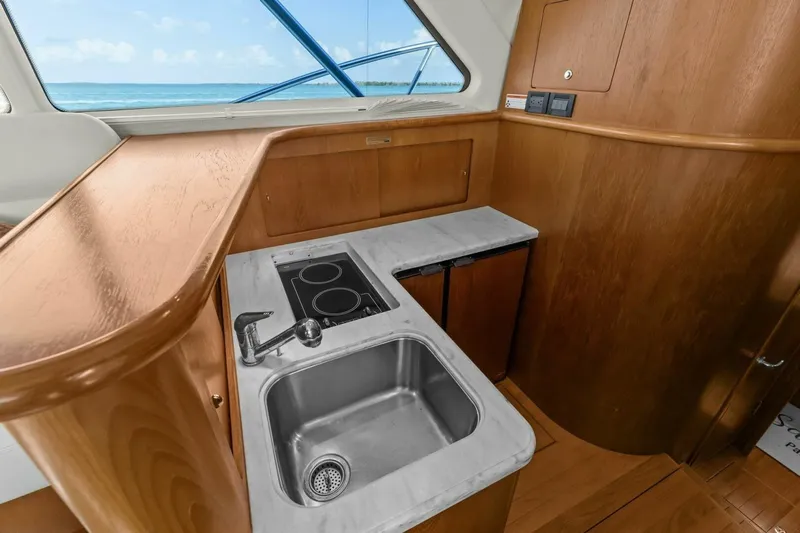 Salty Dach Yacht Photos Pics 2013 Tiara Yachts 3900 Convertible kitchen with sink, stove, and wooden cabinetry.