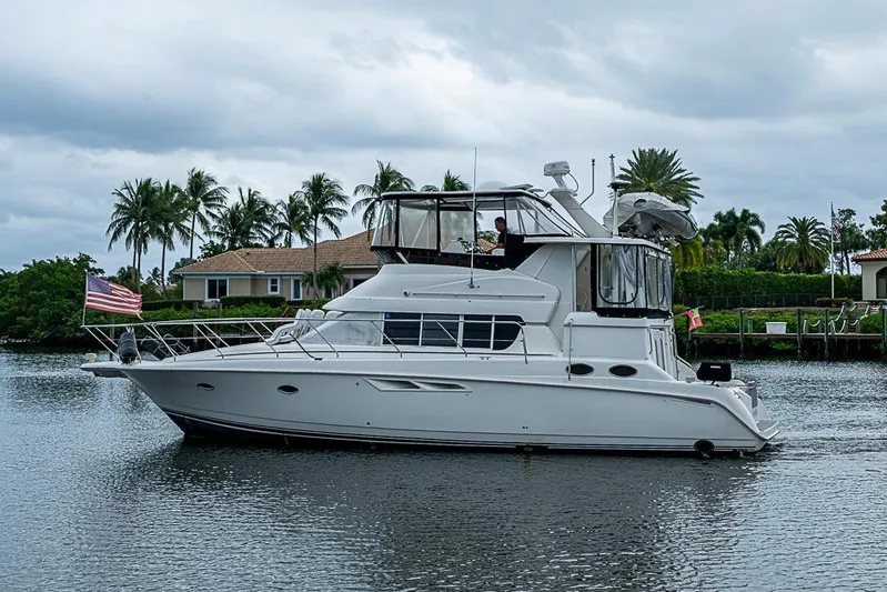 Faintasea Yacht Photos Pics 2000 Silverton 442 Cockpit Motor Yacht on a calm waterway with palm trees.