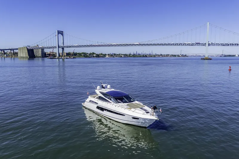  Yacht Photos Pics 2014 Sunseeker 68 Sport Yacht cruising near a large suspension bridge on a sunny day.