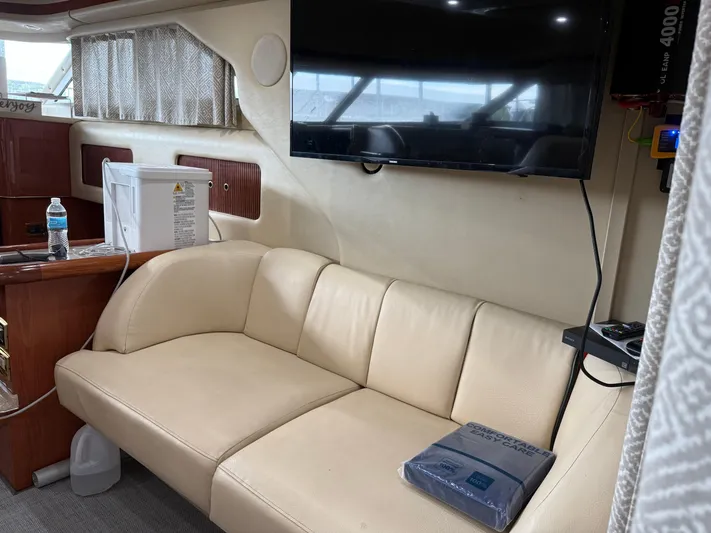 Jet Lag Yacht Photos Pics Interior of 1999 Sea Ray 400 Sedan Bridge with beige sofa and mounted TV.