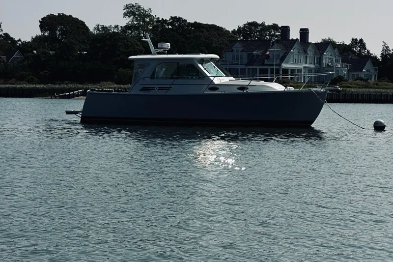 Sister's Yacht Photos Pics 2013 Back Cove 30 boat anchored on calm water near elegant waterfront homes.