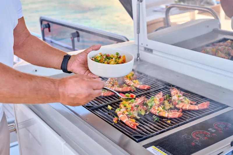  Yacht Photos Pics Grilling seafood on Lagoon Seventy 7 yacht, 2023 model, with fresh vegetable garnish.