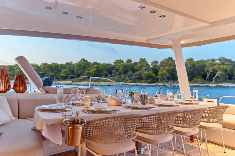  Yacht Photos Pics Luxurious dining setup on 2023 Lagoon Seventy 7 yacht, overlooking serene waters and lush greenery.