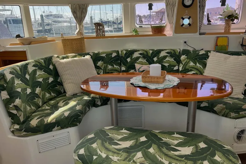 Apres-sea Yacht Photos Pics Cozy interior of 2012 Lagoon 380 S2 catamaran with tropical-themed seating and wooden table.