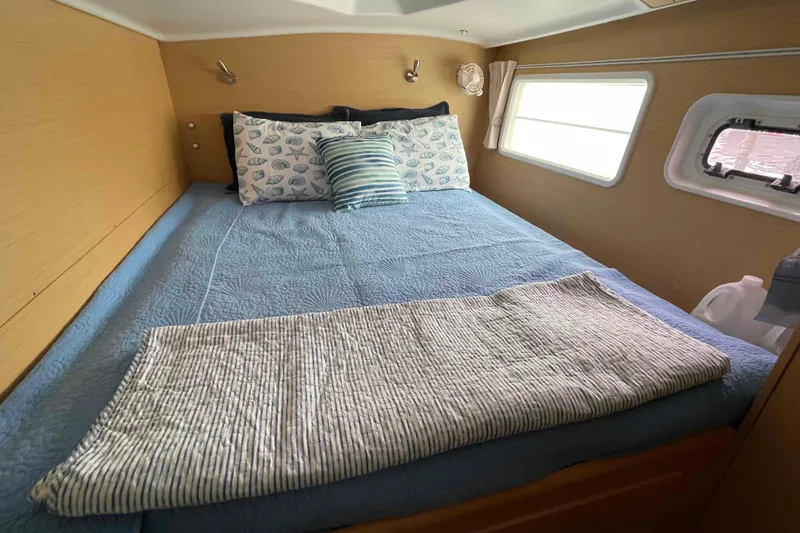 Apres-sea Yacht Photos Pics Cozy bedroom interior of 2012 Lagoon 380 S2 catamaran with blue bedding and decorative pillows.