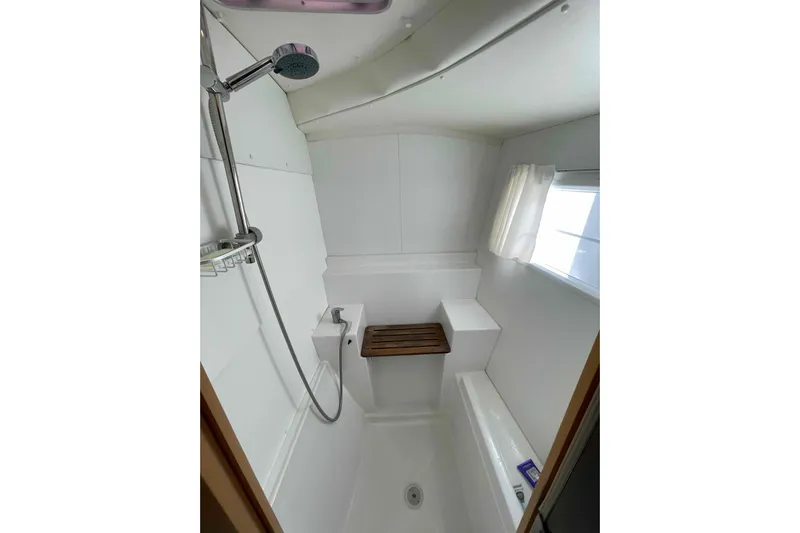 Apres-sea Yacht Photos Pics Compact bathroom with shower in 2012 Lagoon 380 S2 yacht, featuring white interior and window.