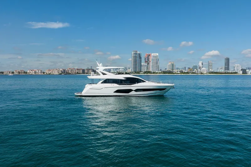 Do It Anyway Yacht Photos Pics 2018 Sunseeker 76 Yacht cruising near city skyline on a clear day.