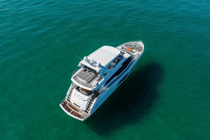 Do It Anyway Yacht Photos Pics 2018 Sunseeker 76 Yacht cruising on clear turquoise waters, aerial view.