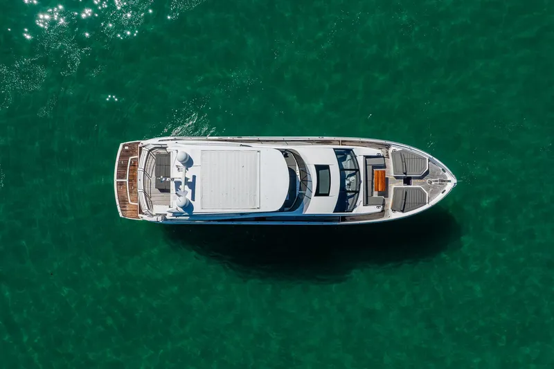 Do It Anyway Yacht Photos Pics Aerial view of 2018 Sunseeker 76 Yacht on clear turquoise water.