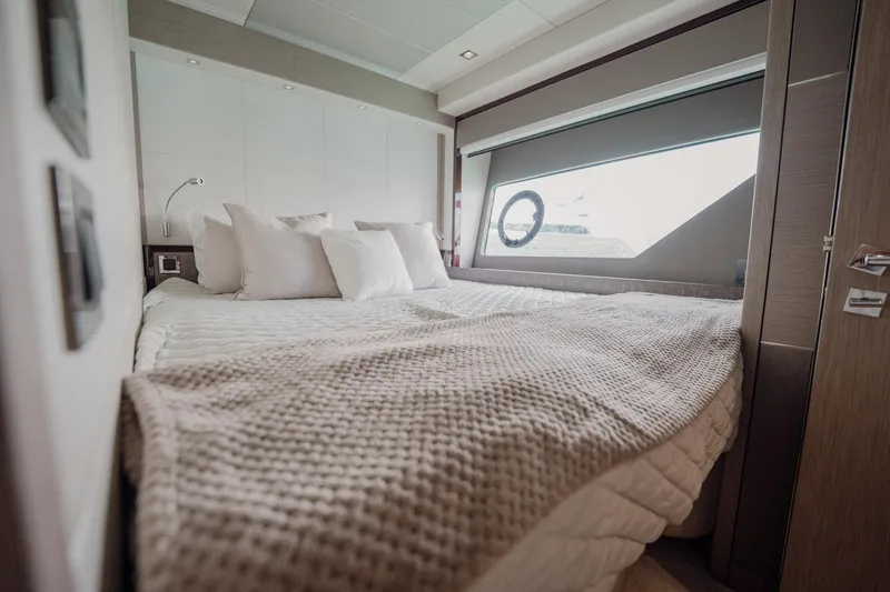 Do It Anyway Yacht Photos Pics Luxurious bedroom interior of 2018 Sunseeker 76 Yacht with cozy bedding and large window.