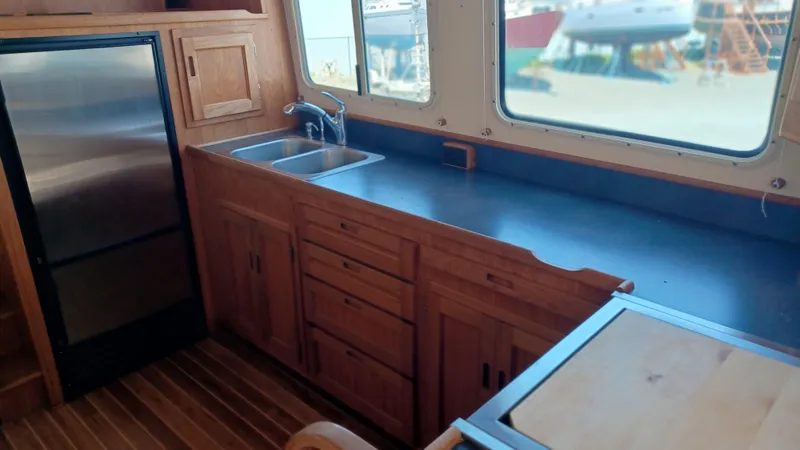 Rafiki Yacht Photos Pics Kitchen area of a 2000 Nordic Tug 37 with wooden cabinets and stainless steel sink.