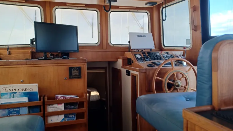 Rafiki Yacht Photos Pics Pilothouse interior of 2000 Nordic Tug 37, featuring wooden helm and navigation equipment.