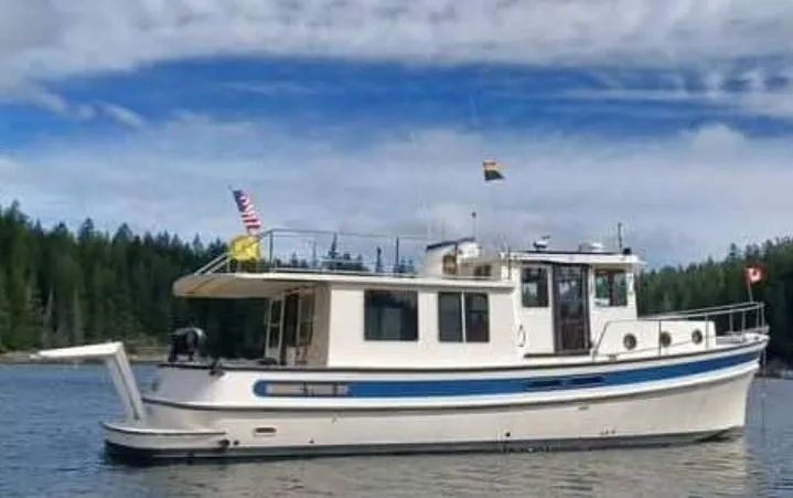 Rafiki Yacht Photos Pics 2000 Nordic Tug 37 boat on a serene lake with forested background.