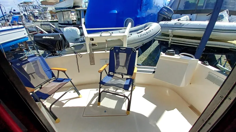 Rafiki Yacht Photos Pics Two chairs on the deck of a 2000 Nordic Tug 37, with boats in the background.