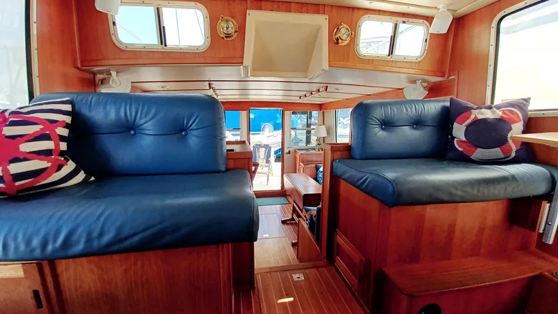 Rafiki Yacht Photos Pics Interior of 2000 Nordic Tug 37 with blue leather seating and nautical-themed pillows.