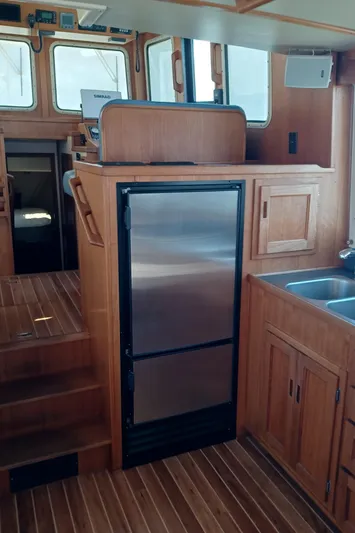Rafiki Yacht Photos Pics Interior of 2000 Nordic Tug 37 with wooden cabinetry and stainless steel fridge.