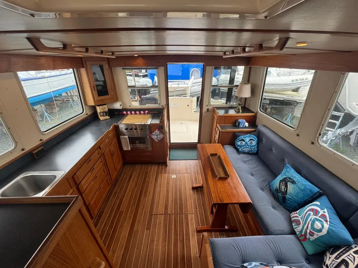 Rafiki Yacht Photos Pics Interior of 2000 Nordic Tug 37 with wood flooring, kitchen, and seating area.
