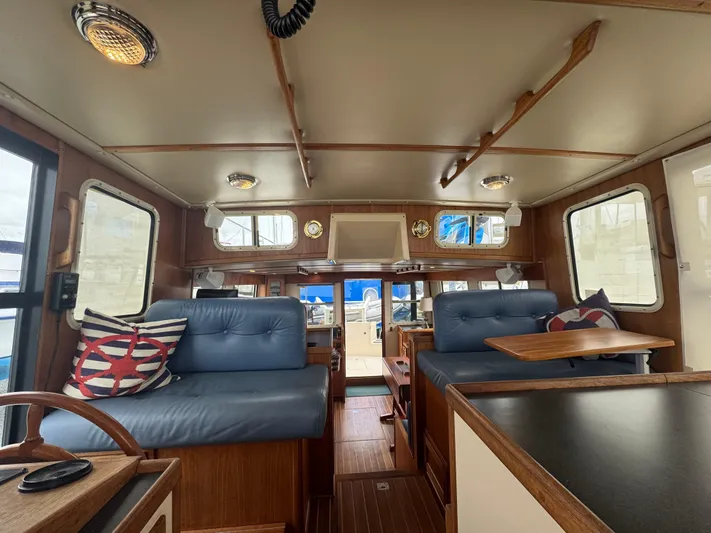 Rafiki Yacht Photos Pics Interior of a 2000 Nordic Tug 37 boat with blue seating and wooden accents.