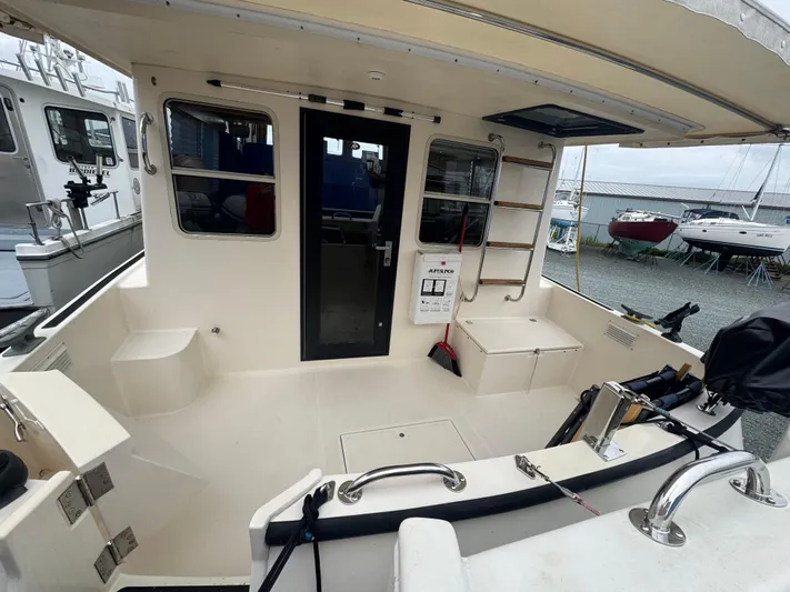 Rafiki Yacht Photos Pics Nordic Tug 37, 2000 model, spacious deck area with seating and ladder, docked near other boats.