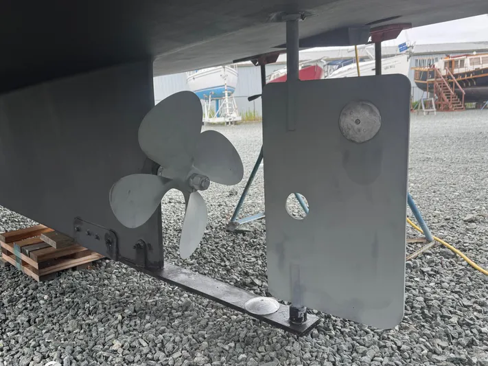 Rafiki Yacht Photos Pics Nordic Tug 37 (2000) propeller and rudder detail on gravel surface.