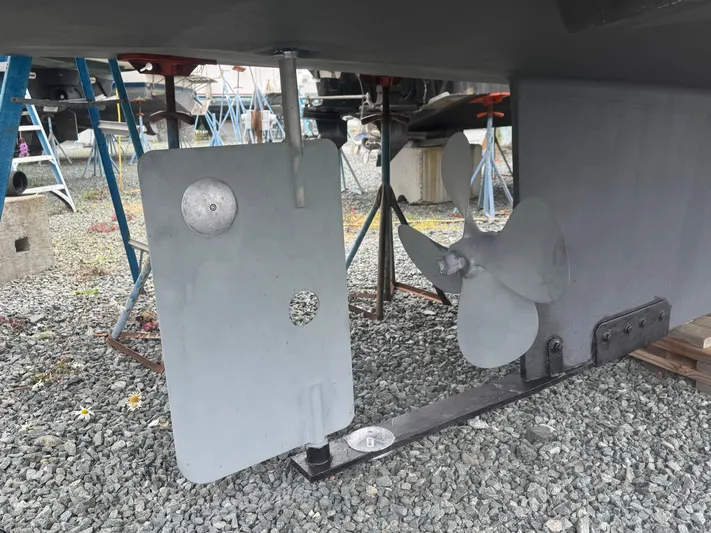 Rafiki Yacht Photos Pics Nordic Tug 37 (2000) propeller and rudder on gravel, with maintenance equipment nearby.