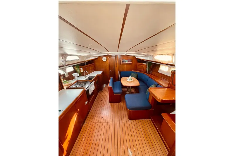 Further Yacht Photos Pics Interior of 2005 Beneteau Oceanis 473 yacht with wooden flooring and blue seating.