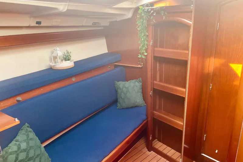 Further Yacht Photos Pics Interior of 2005 Beneteau Oceanis 473 sailboat with blue seating and wooden cabinetry.