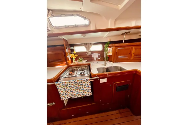 Further Yacht Photos Pics 2005 Beneteau Oceanis 473 yacht kitchen with stove, sink, and wooden cabinetry.