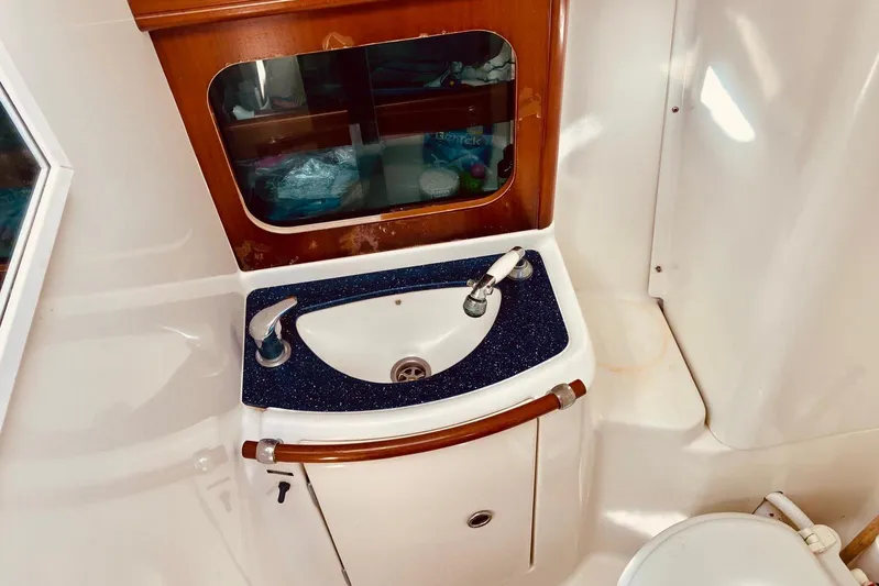 Further Yacht Photos Pics Beneteau Oceanis 473 (2005) bathroom sink with wooden cabinet and mirror.