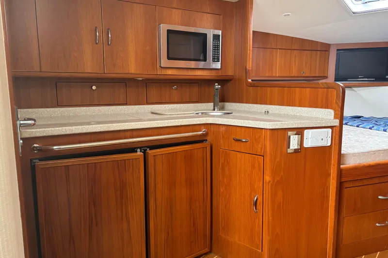  Yacht Photos Pics 2010 Cabo 36 Express yacht interior with wooden cabinetry, microwave, and compact kitchen area.